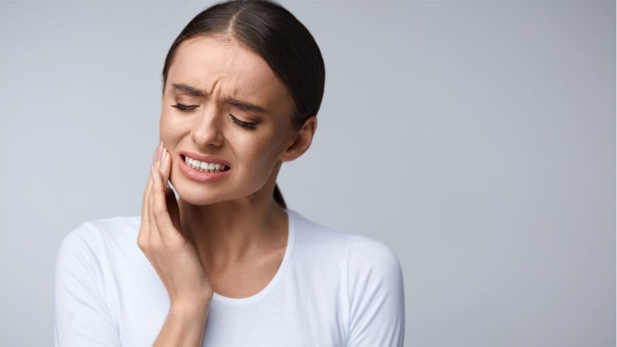 Femme ressentant une douleur dentaire, main sur la joue
